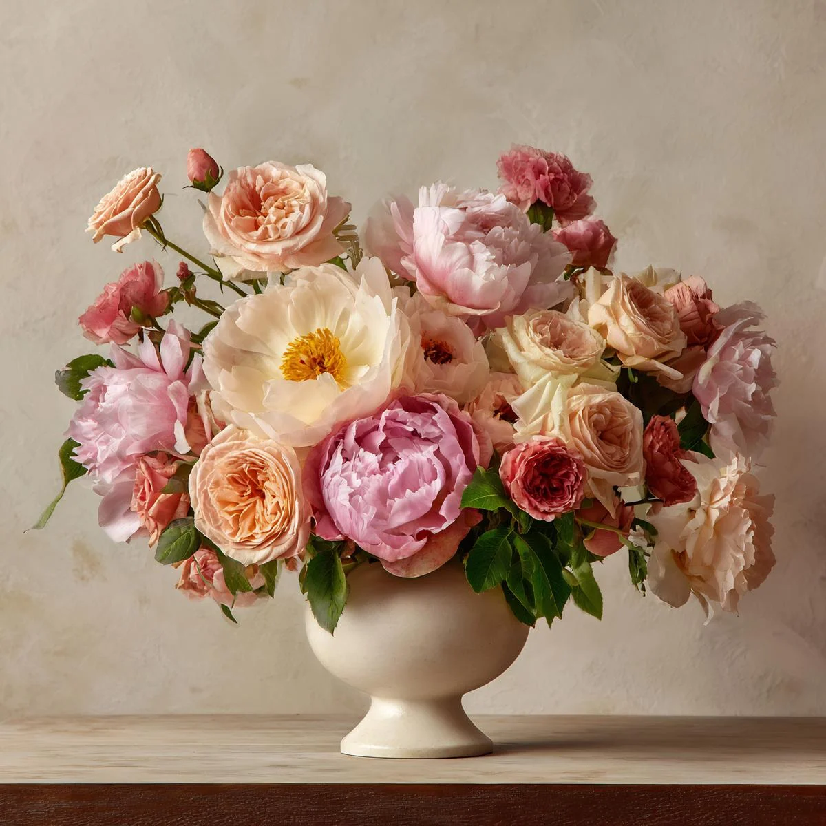 Pastel pink peonies and blush garden roses in a cream urn vase