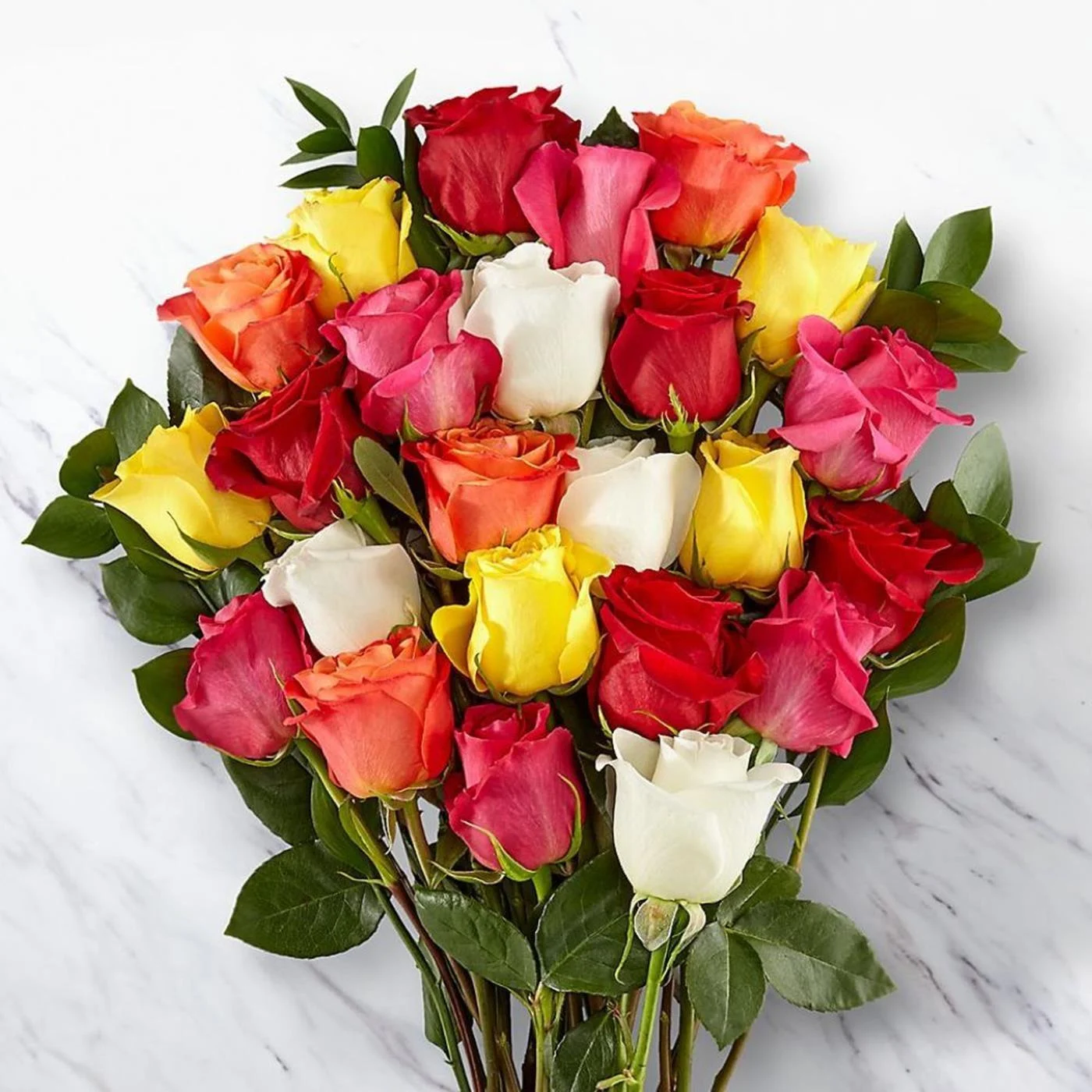 Overhead view of pink yellow orange red and white roses on a light marble surface